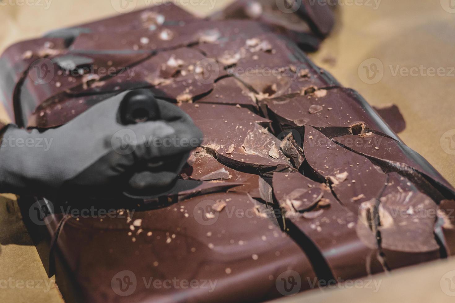 persona che rompe un grosso blocco di cioccolato in pezzi foto