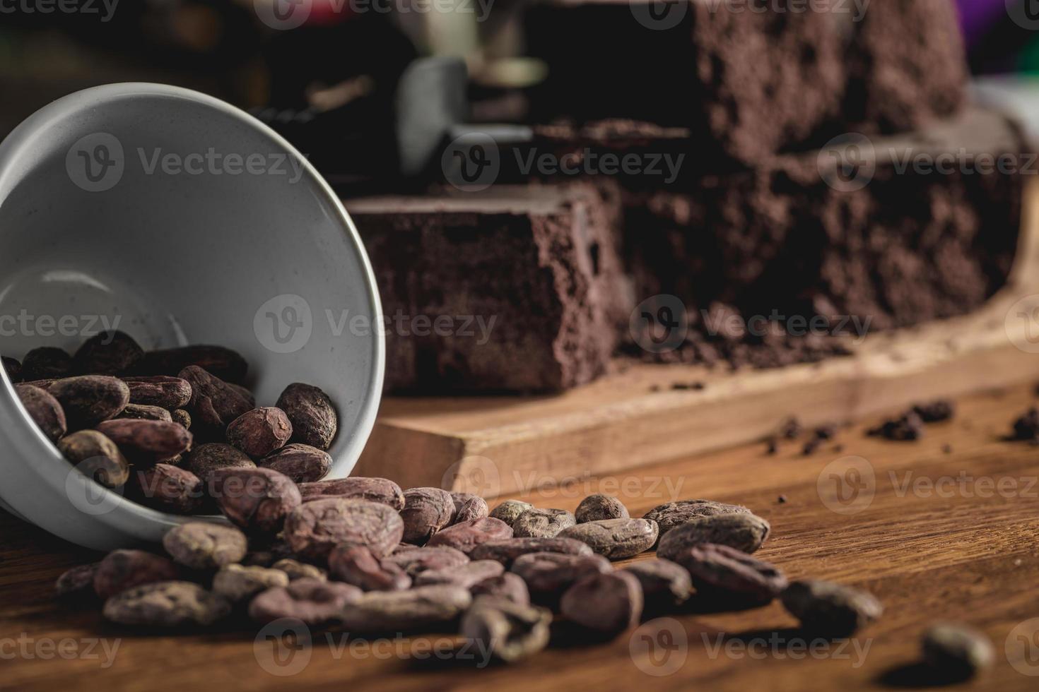 disposizione di fave di cacao e barrette di cioccolato su superficie in legno. foto