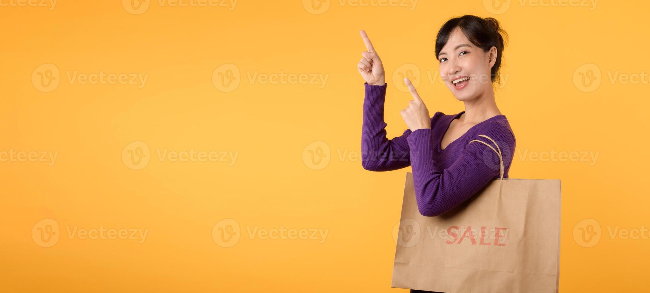 un attraente modello, vestito nel un' viola camicia e Tenere un' shopping Borsa, simboleggia il gioia di un' riuscito shopping baldoria nel un' Al dettaglio memorizzare contro un' giallo sfondo. foto