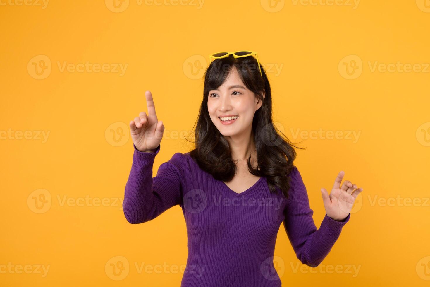 giovane asiatico donna 30s indossare viola camicia e giallo occhiali da sole su testa contento Sorridi espressione toccante virtuale schermo isolato su giallo sfondo. tecnologia concetto. foto