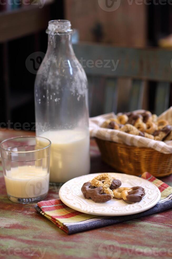 vaniglia biscotti con cioccolato glassatura e un' bicchiere di latte foto