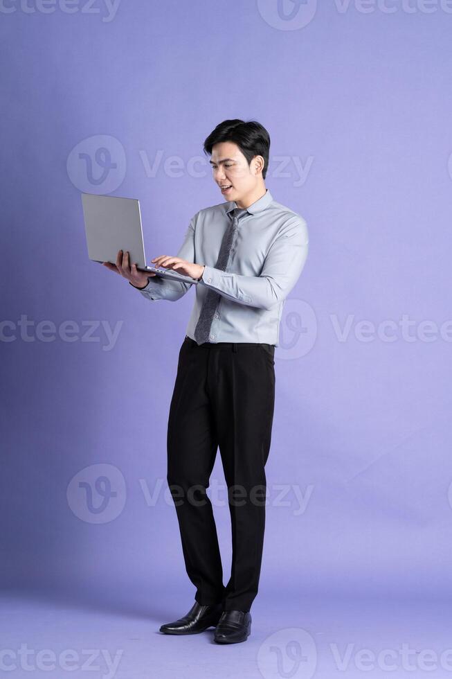 ritratto di asiatico maschio uomo d'affari in piedi e in posa su viola sfondo foto