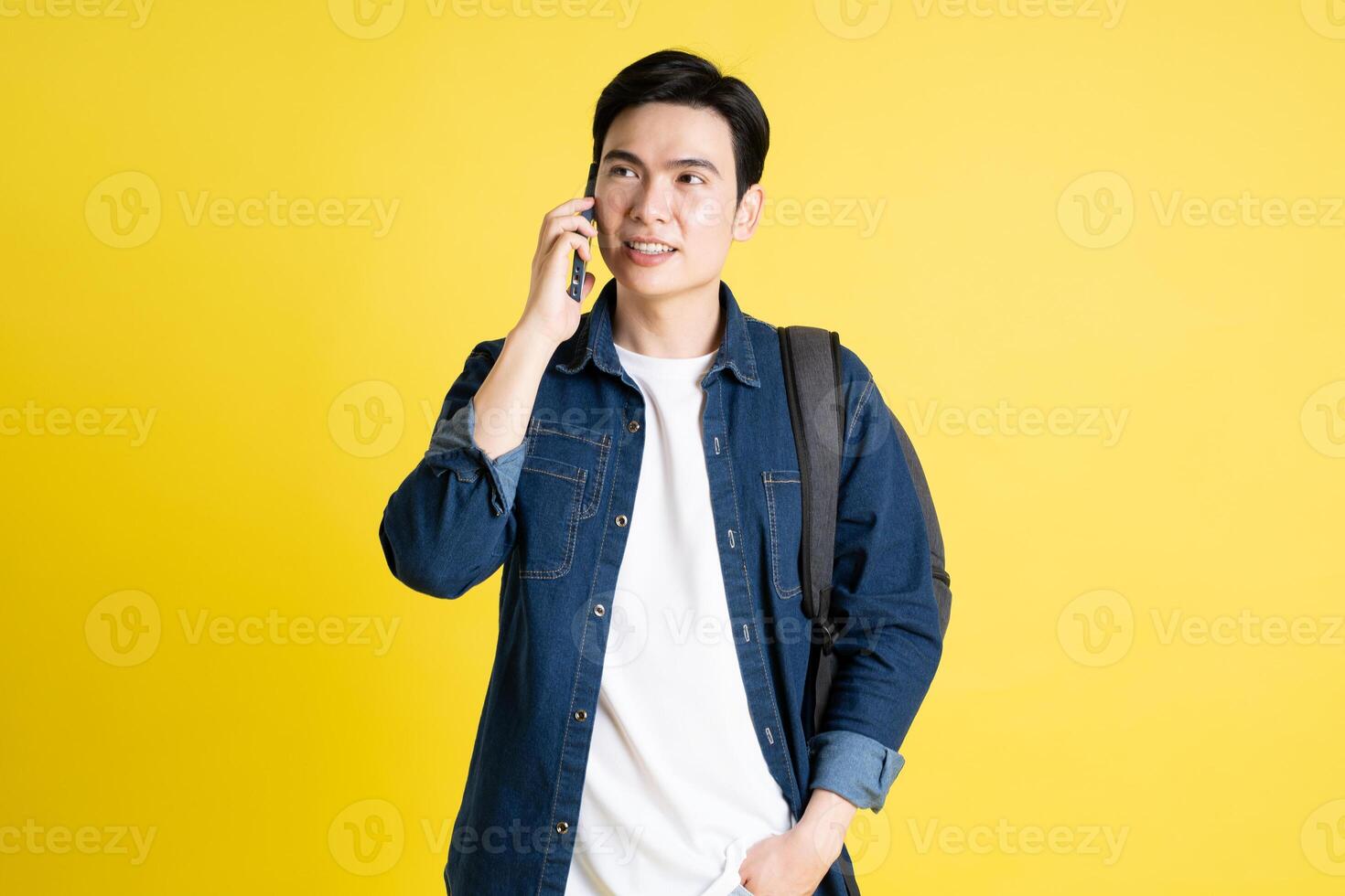 ritratto di asiatico maschio alunno in posa su giallo sfondo foto
