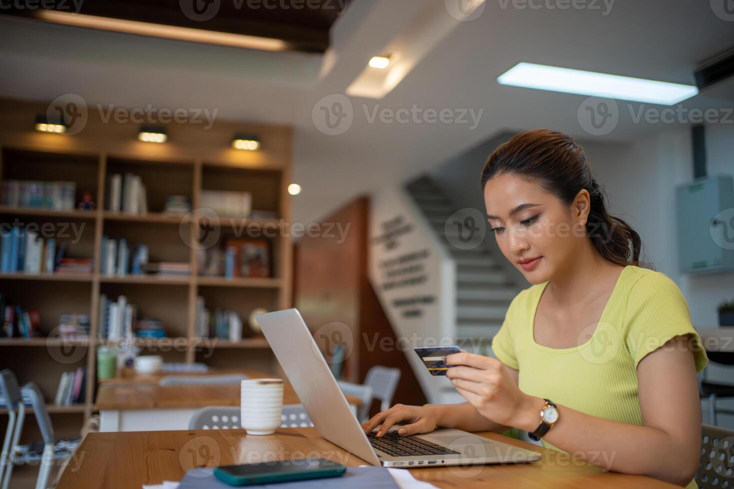 asiatico donna seduta e Tenere credito carta per in linea shopping di il computer portatile e inteligente Telefono a casa. foto