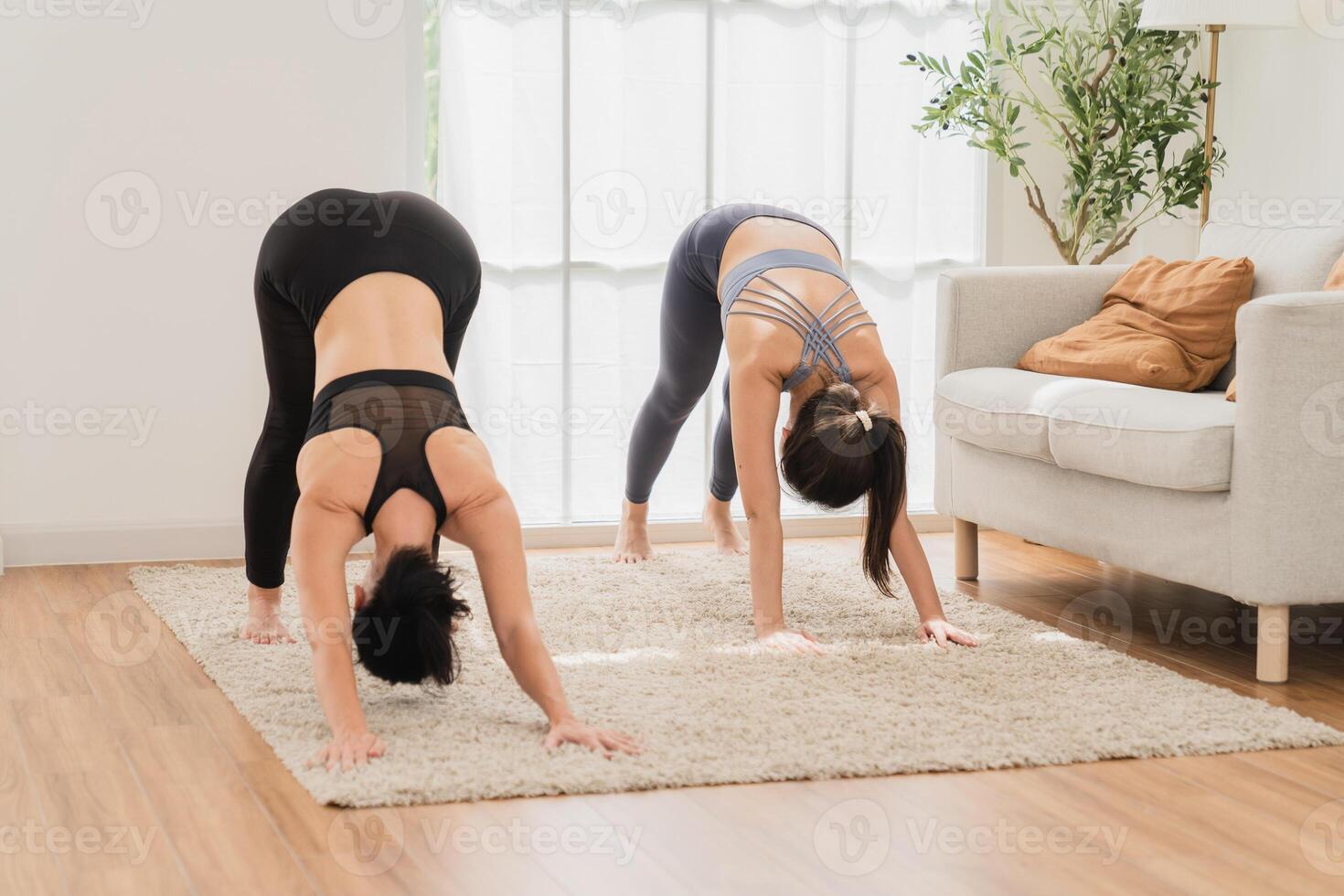 un' giovane in forma donna pratiche yoga di fare asana nel un' luminosa yoga studio. yoga professionista con studenti nel yoga classe. foto