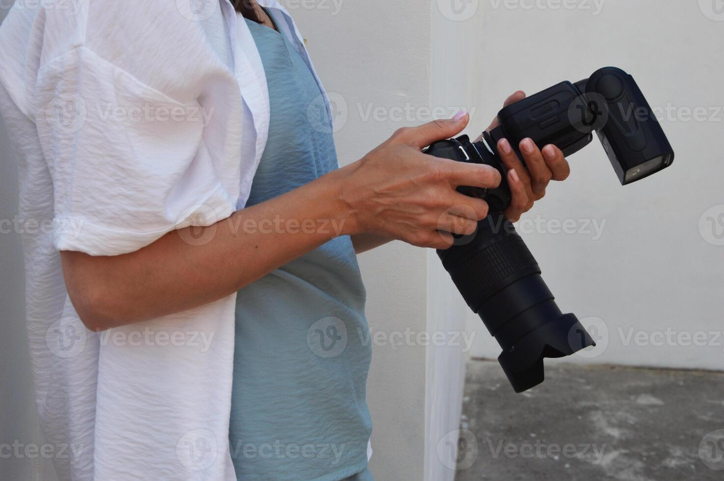 un' donna è Tenere un' telecamera con un' veloce. professionale fotografo con un' telecamera nel il suo mani. foto