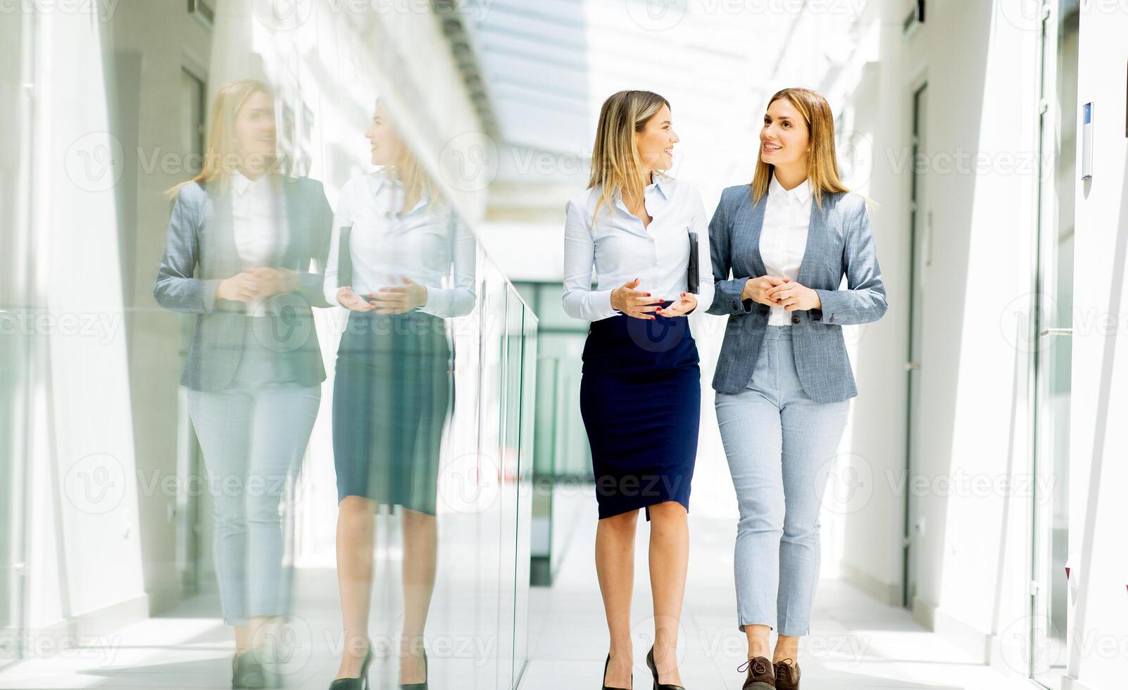 Due giovane attività commerciale donne a piedi e discutere nel il ufficio corridoio foto