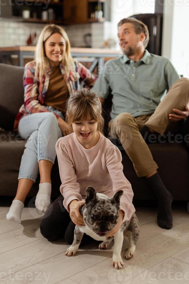 famiglia bonding tempo con giocoso francese bulldog cucciolo nel accogliente vivente camera foto