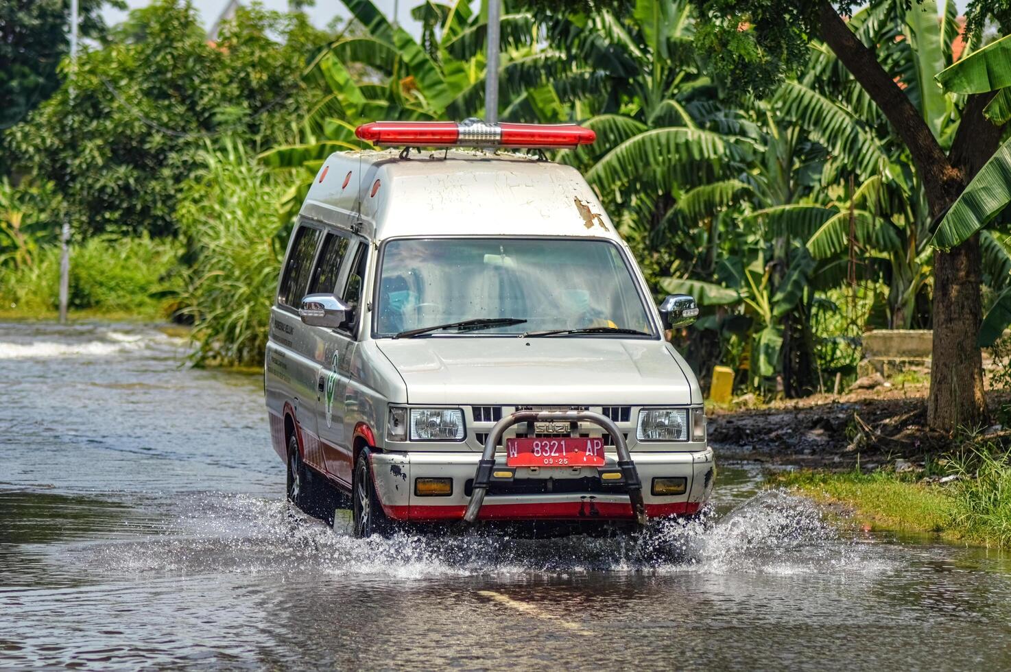 un ambulanza passaggio attraverso alluvione acque nel greco reggenza, Indonesia, 21 febbraio 2024. foto