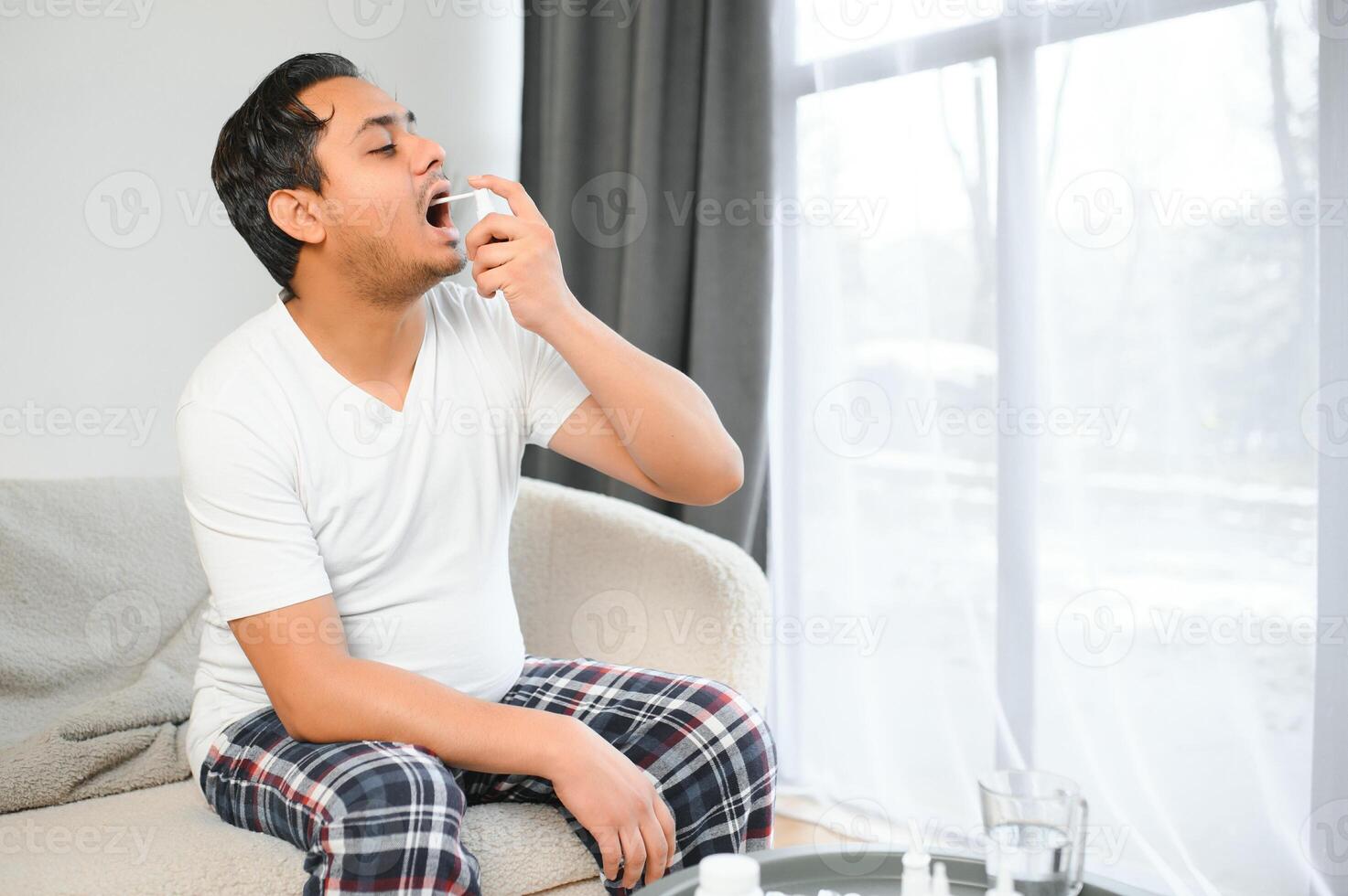 un indiano uomo ha il influenza. un' uomo usi un' gola spray. foto