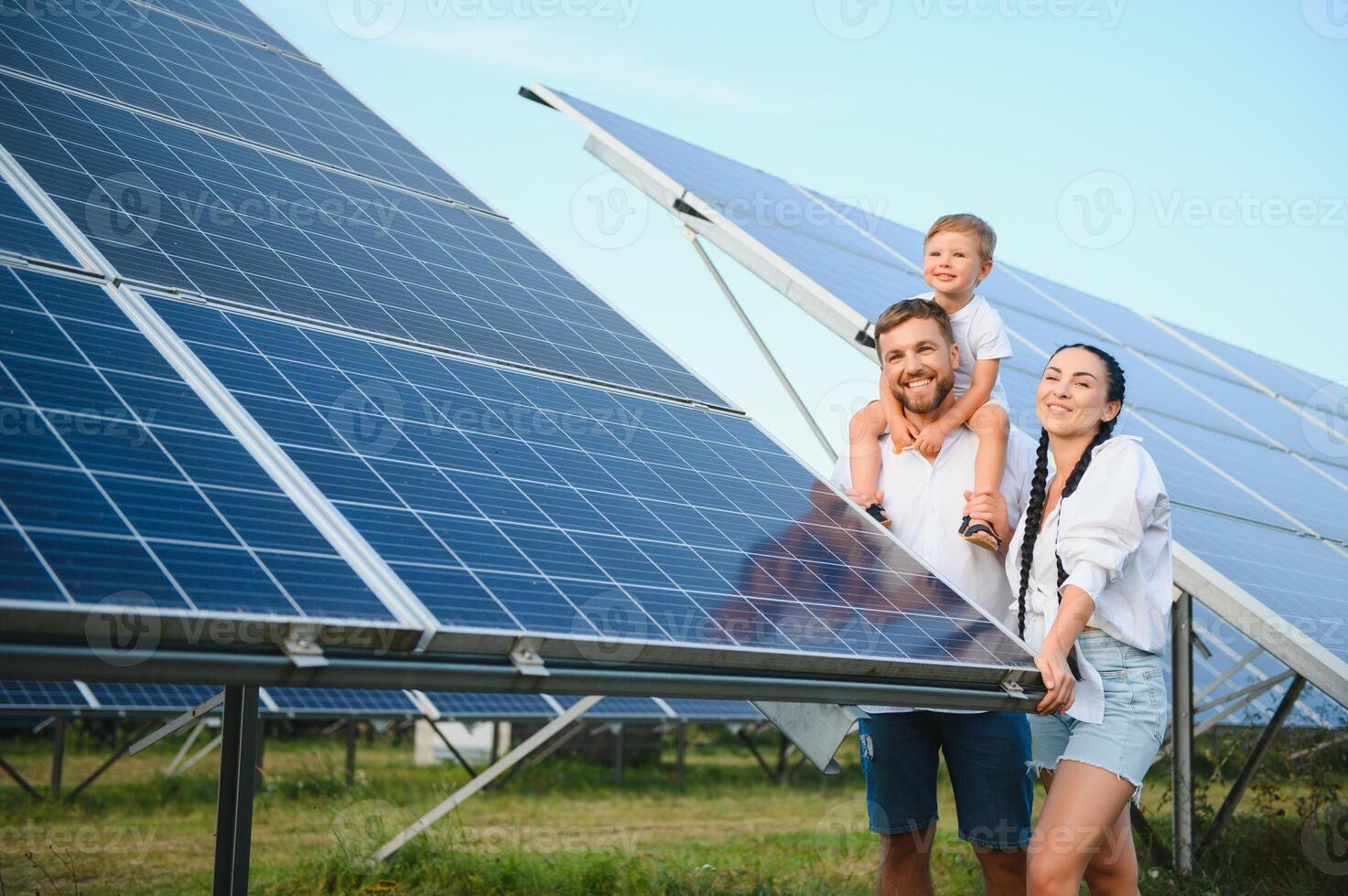 un' largo tiro di un' contento famiglia in piedi insieme e sorridente a telecamera con un' grande solare pannello nel sfondo foto