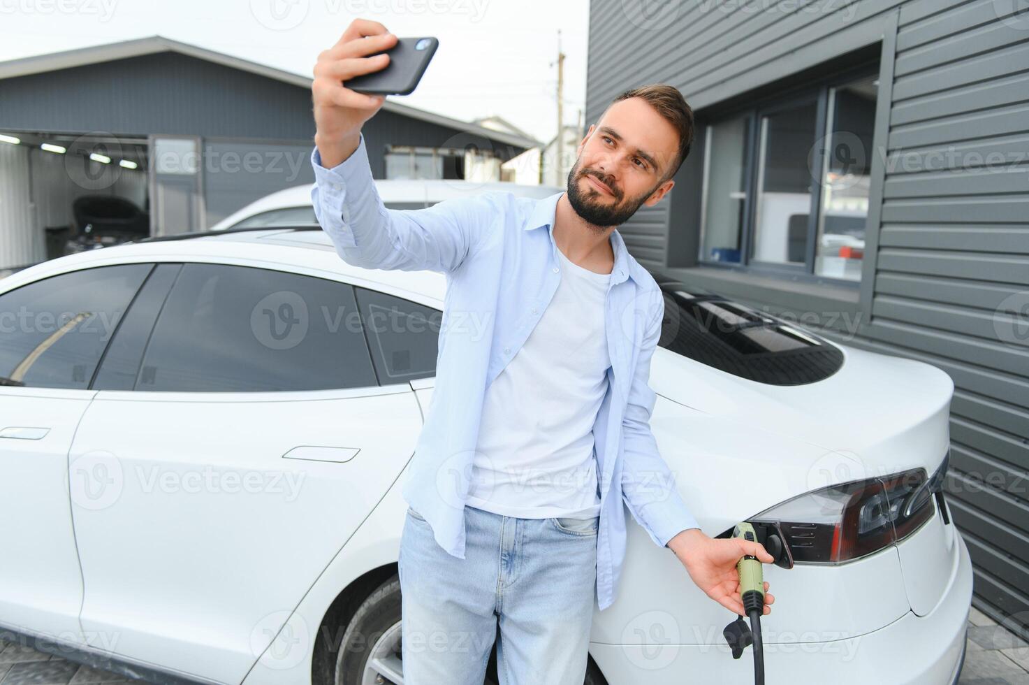 contento uomo utilizzando inteligente Telefono e ricarica auto a veicolo ricarica stazione foto