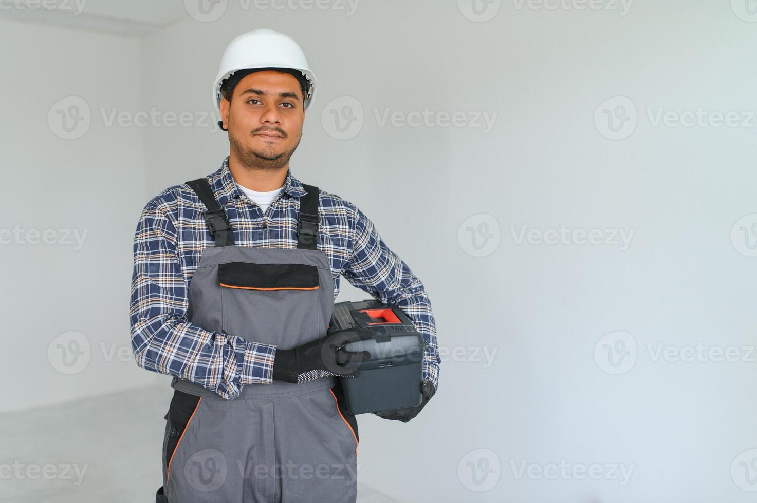 professione, costruzione e edificio - contento sorridente indiano lavoratore o costruttore nel casco al di sopra di grigio sfondo. foto