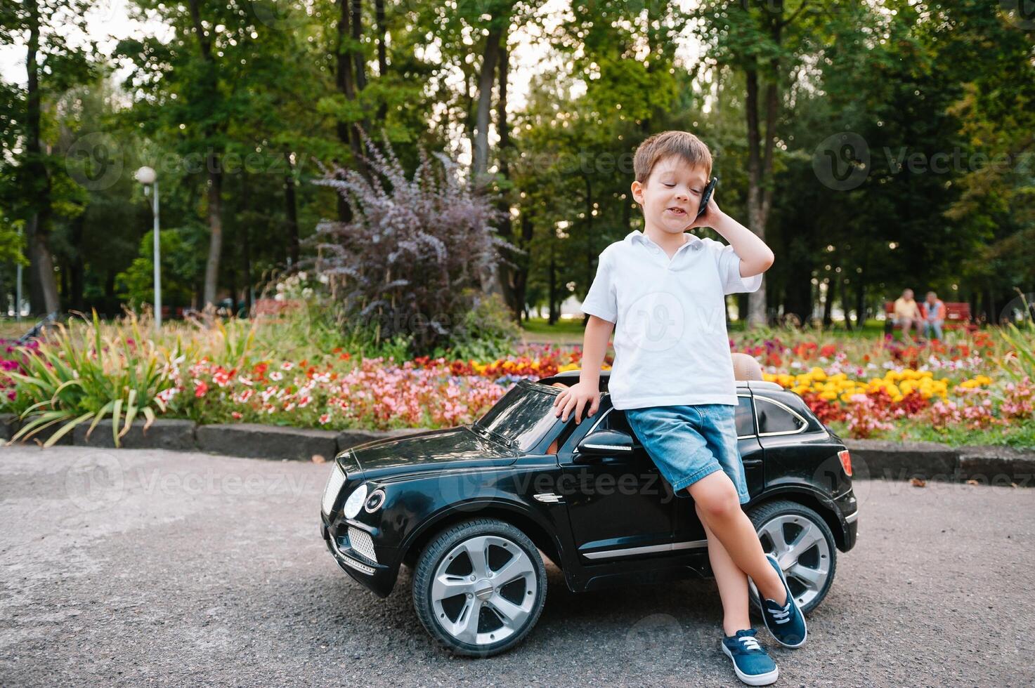 carino ragazzo nel equitazione un' nero elettrico auto nel il parco. divertente ragazzo cavalcate su un' giocattolo elettrico macchina. copia spazio. foto