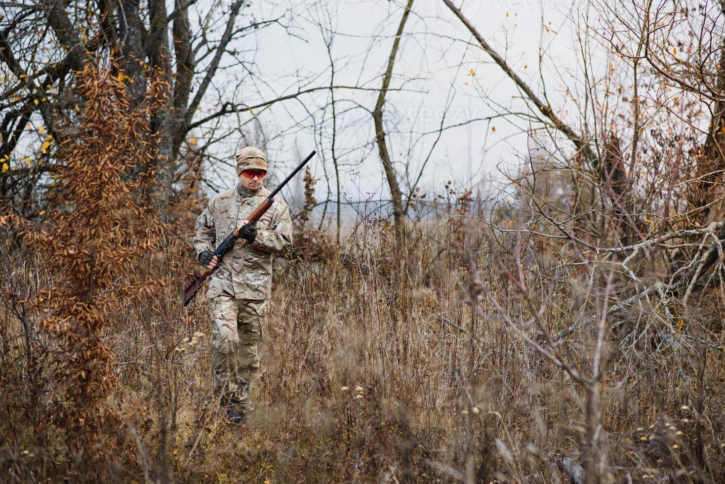 cacciatore bello tipo con arma. cacciatore trascorrere tempo libero a caccia. a caccia attrezzatura. brutale maschile passatempo. uomo osservando natura sfondo. cacciatore hold fucile. sicurezza le misure. naturale ambiente foto