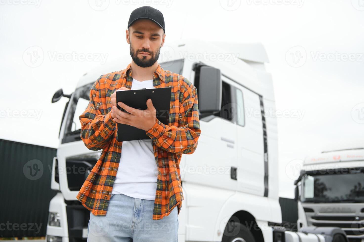 camion autista controllo spedizione elenco mentre in piedi su parcheggio lotto di distribuzione magazzino foto