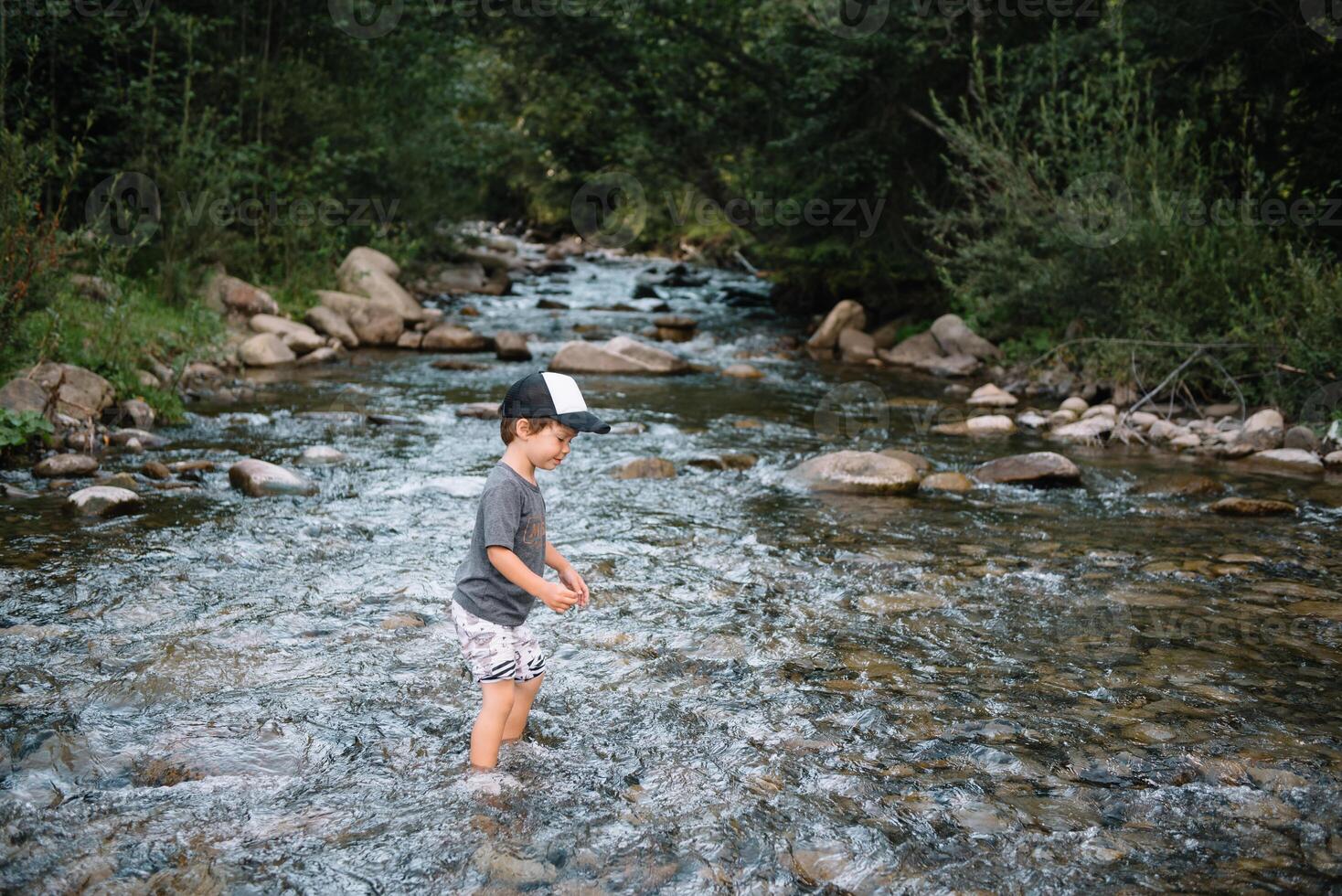 contento ragazzo su un' camminare vicino il fiume nel il montagne foto