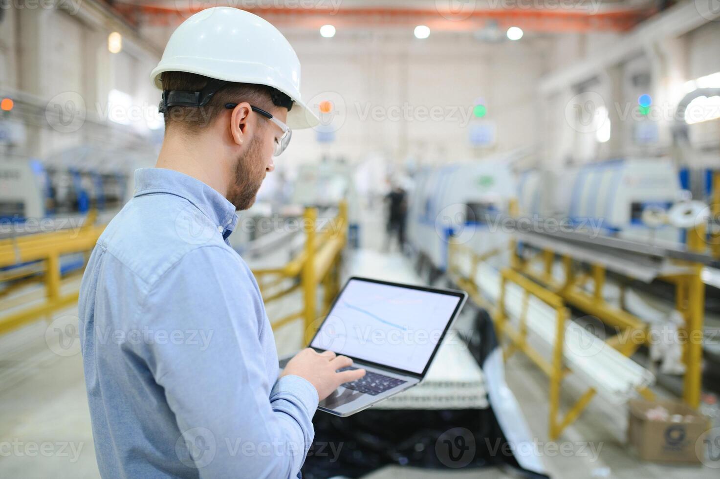 lato Visualizza di tecnico o ingegnere con cuffia e il computer portatile in piedi nel industriale fabbrica foto