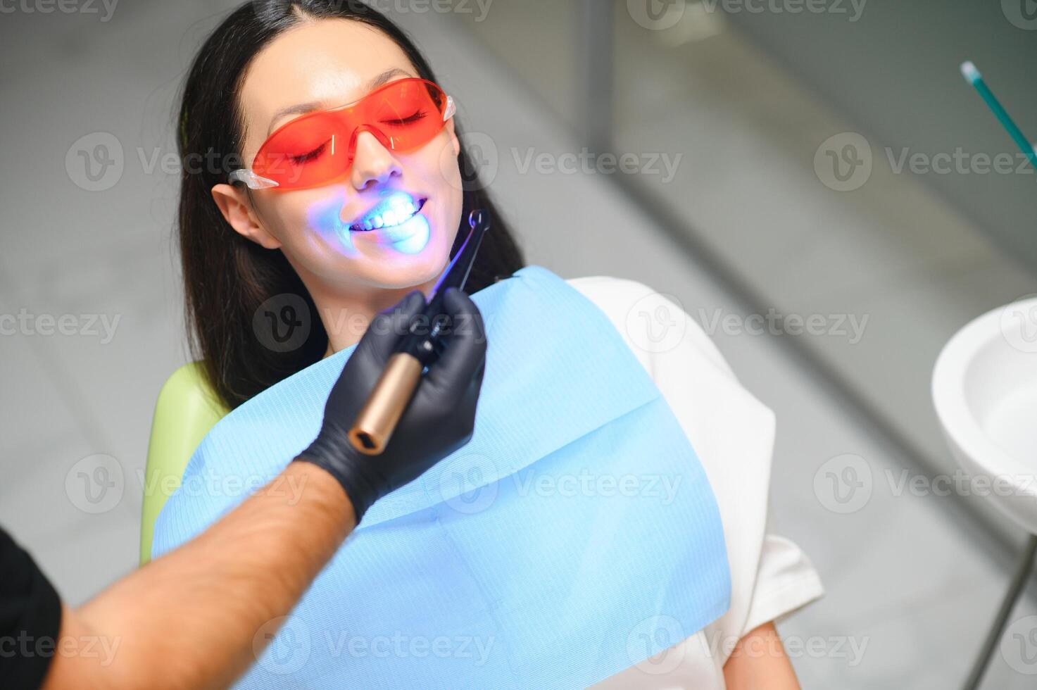 giovane donna ottenere dentale Riempimento essiccazione procedura con curare uv leggero a dentale clinica foto