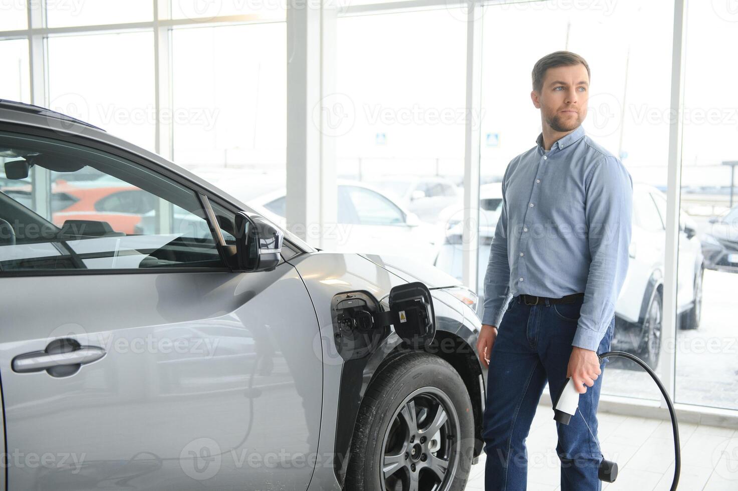 barba uomo provando un' nuovo ricarica cavo con un' auto ricarica stazione a il il motore concessionaria. concetto di acquisto elettrico veicolo. inteligente ecologico vivente foto