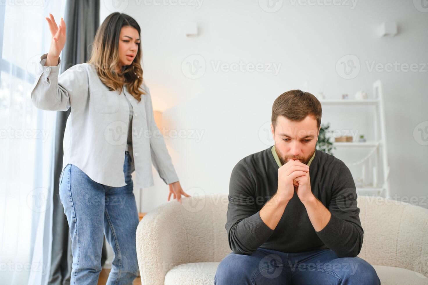 coppia discutere. moglie urlando per sua disperato marito seduta su un' divano nel il vivente camera a casa foto