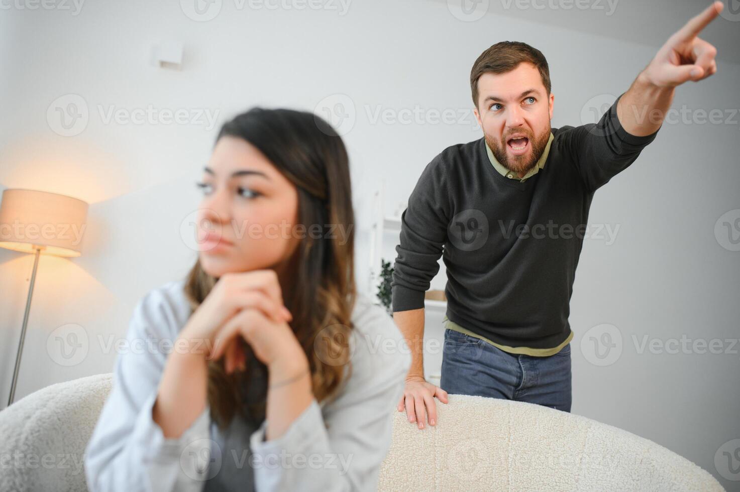 un agitato e irritato marito grida e sembra a il suo moglie, un' litigare fra coniugi. famiglia malinteso, litigare foto