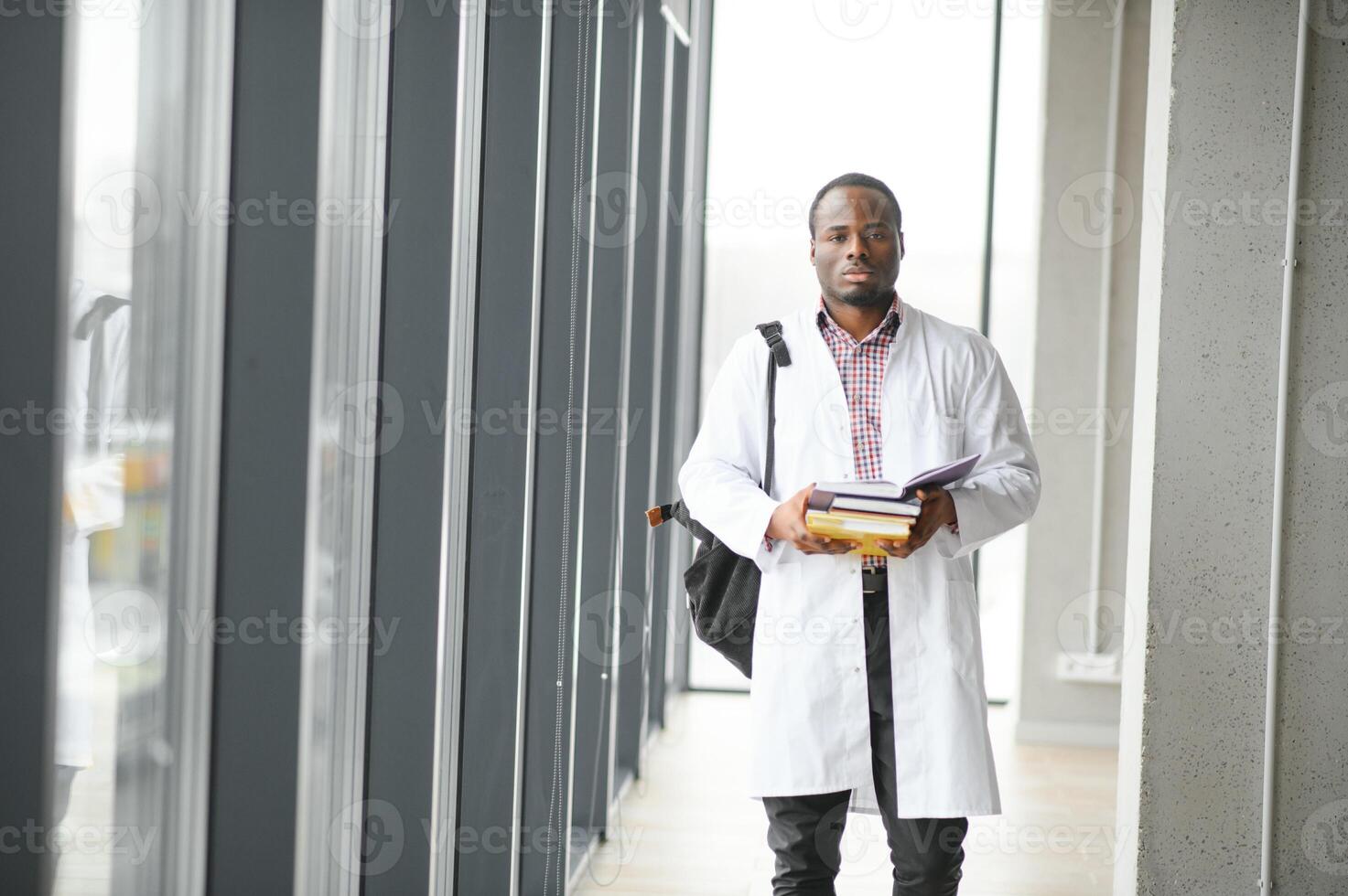 nero maschio medico alunno indossare un' laboratorio cappotto con libro foto