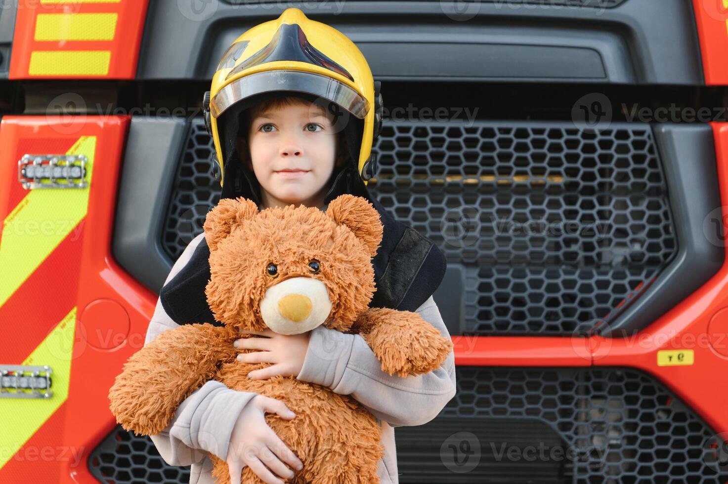 un' ragazzo indossare un' dei vigili del fuoco casco vicino un' fuoco camion. foto