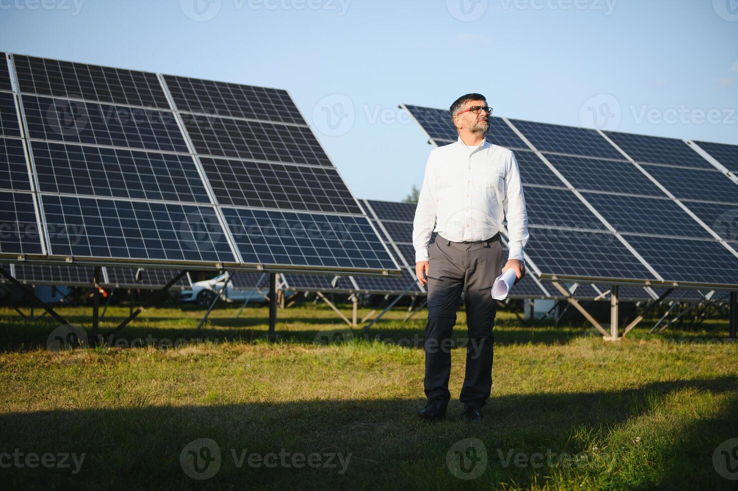 industriale anziano uomo ingegnere a piedi attraverso solare pannello campo per visita medica foto