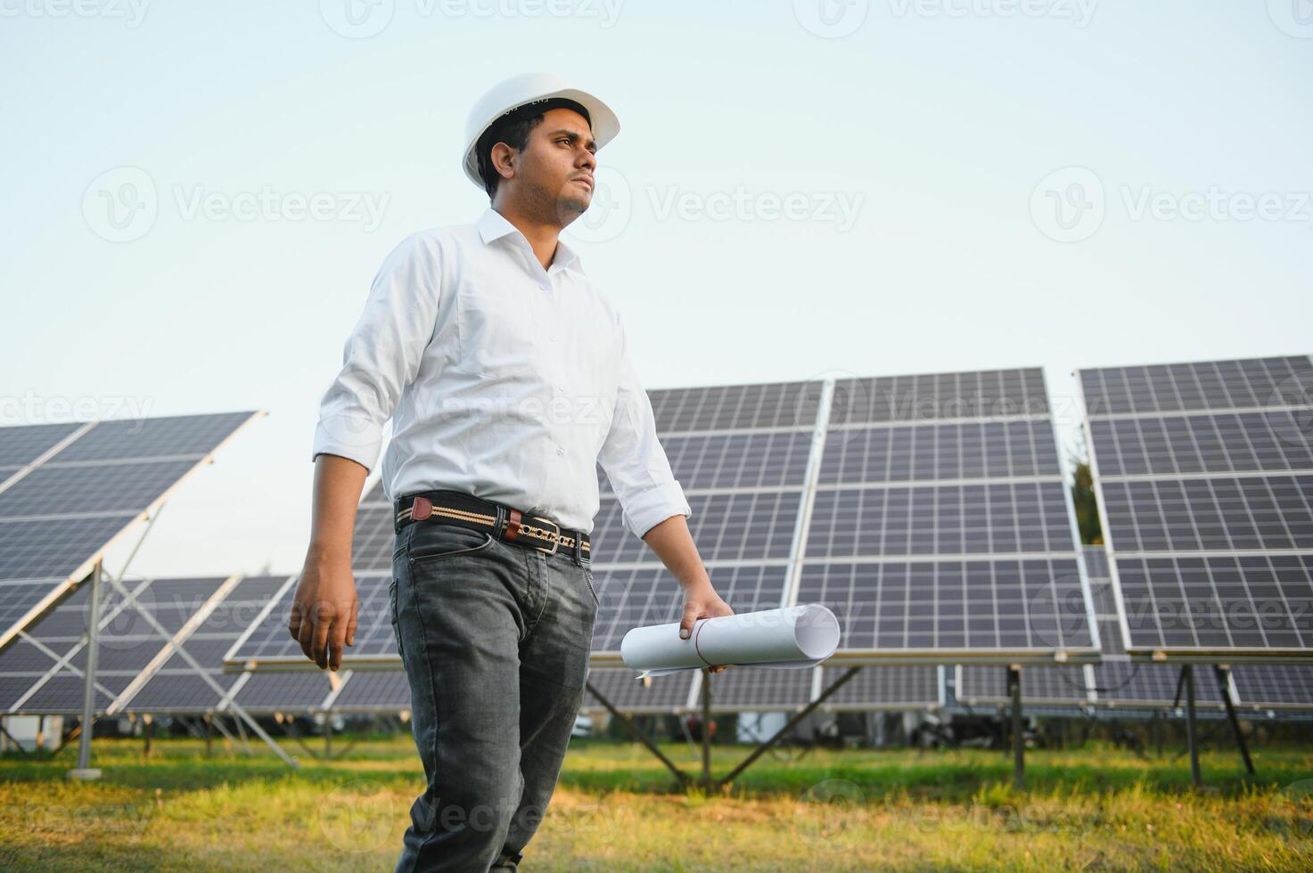 ritratto di giovane indiano maschio ingegnere in piedi vicino solare pannelli, con chiaro blu cielo sfondo, rinnovabile e pulito energia. abilità India, copia spazio foto