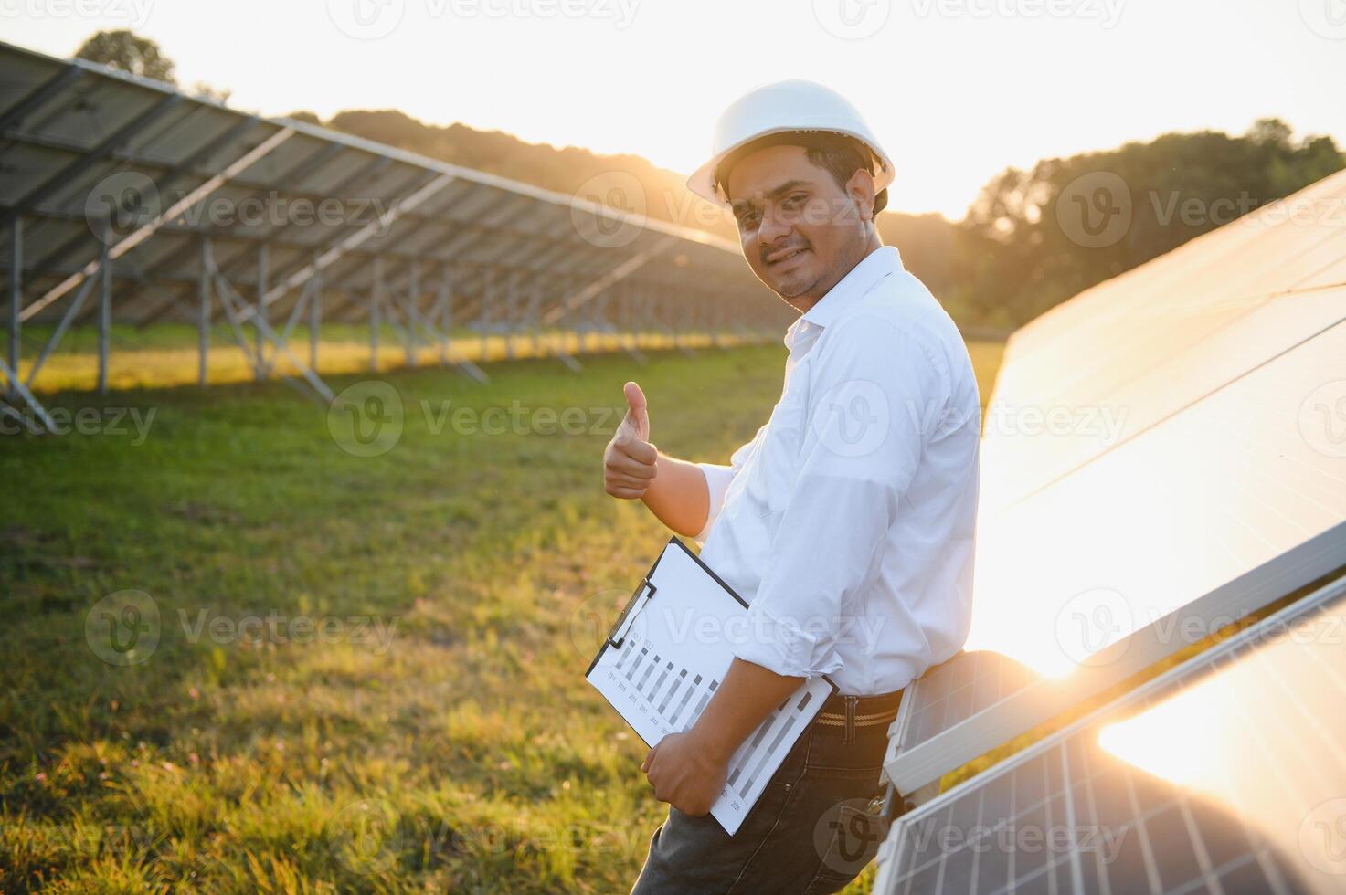 ritratto di giovane indiano maschio ingegnere in piedi vicino solare pannelli, con chiaro blu cielo sfondo, rinnovabile e pulito energia. abilità India, copia spazio foto