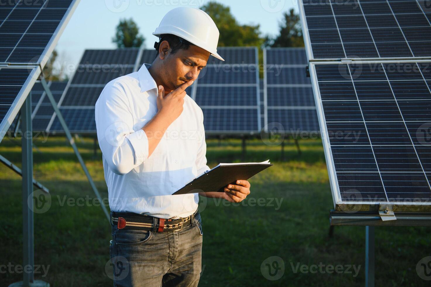 ritratto di giovane indiano maschio ingegnere in piedi vicino solare pannelli, con chiaro blu cielo sfondo, rinnovabile e pulito energia. abilità India, copia spazio foto