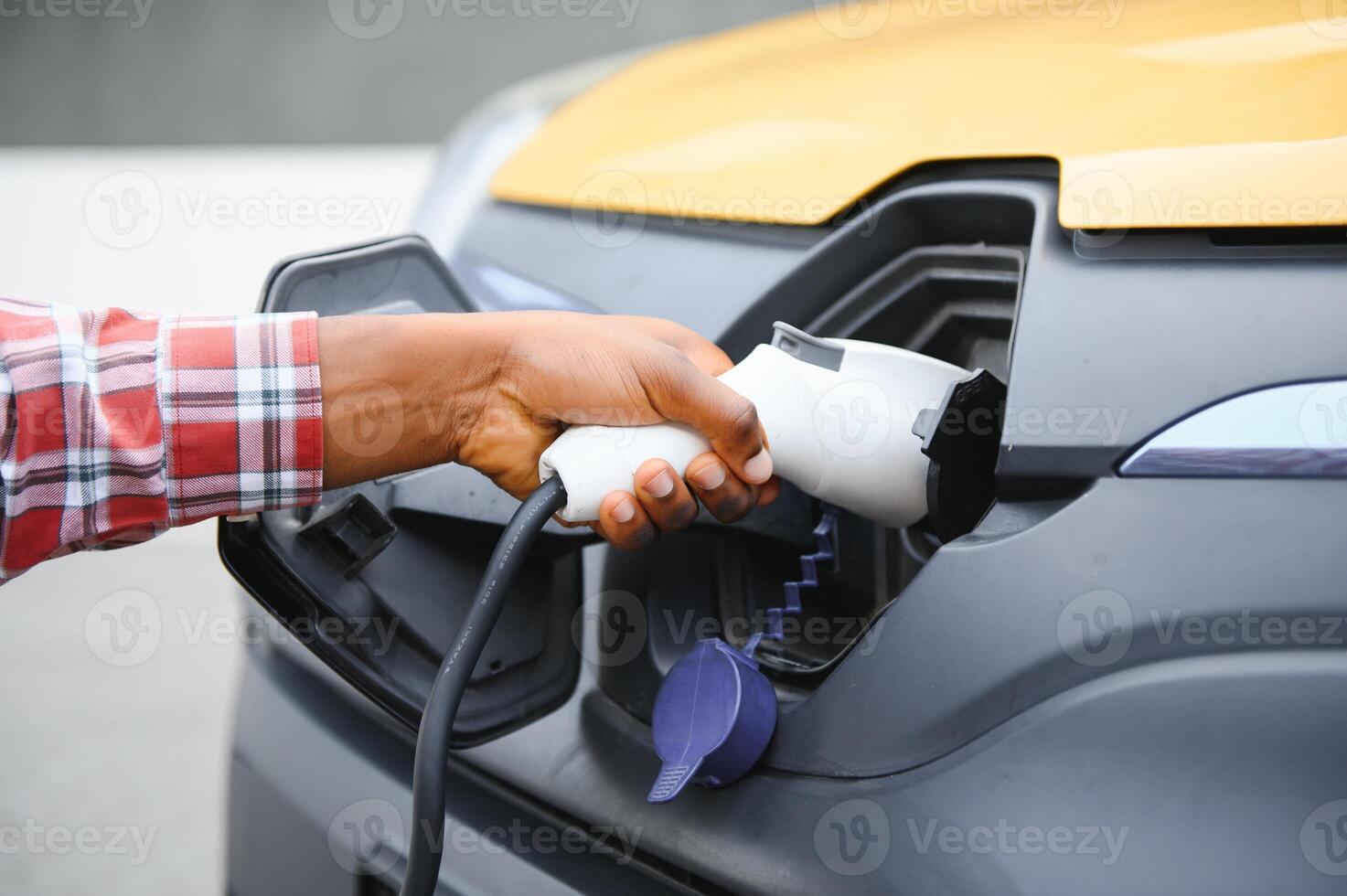 africano americano uomo ricarica il suo elettrico macchina. foto