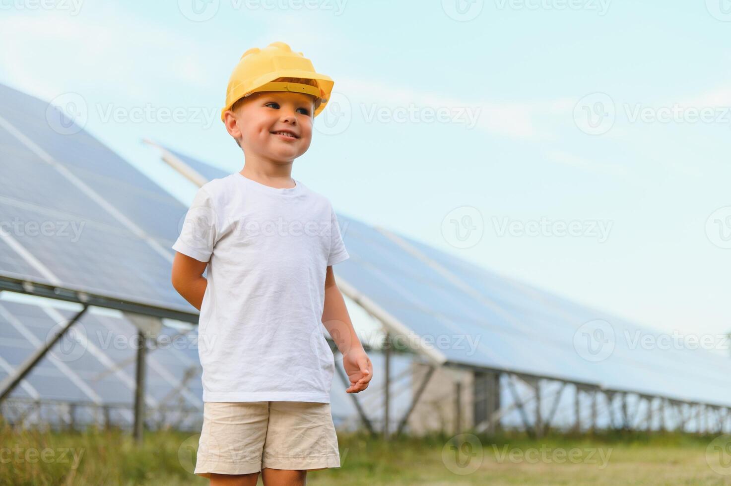 ritratto di un' bambino vicino il solare pannelli. un' poco ragazzo nel un' protettivo casco vicino solare pannelli con il suo mano. tiro a un' solare energia pianta. ecologico azienda agricola. solare energia stazione. persone foto
