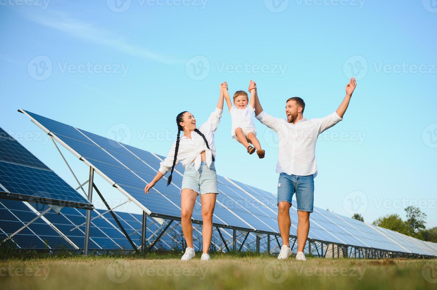 giovane famiglia di tre è accovacciato vicino fotovoltaico solare pannello, poco ragazzo e genitori. moderno famiglia concetto. il concetto di verde energia foto