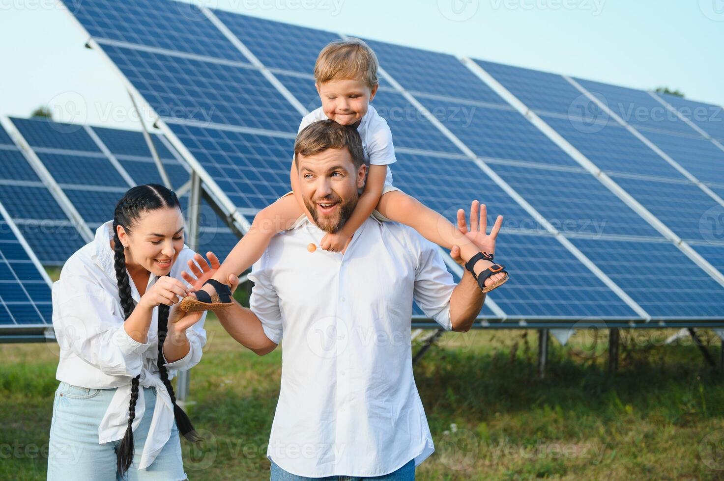 giovane famiglia con un' piccolo bambino nel sua braccia su un' sfondo di solare pannelli. un' uomo e un' donna Guarda a ogni altro con amore. solare energia concetto. foto