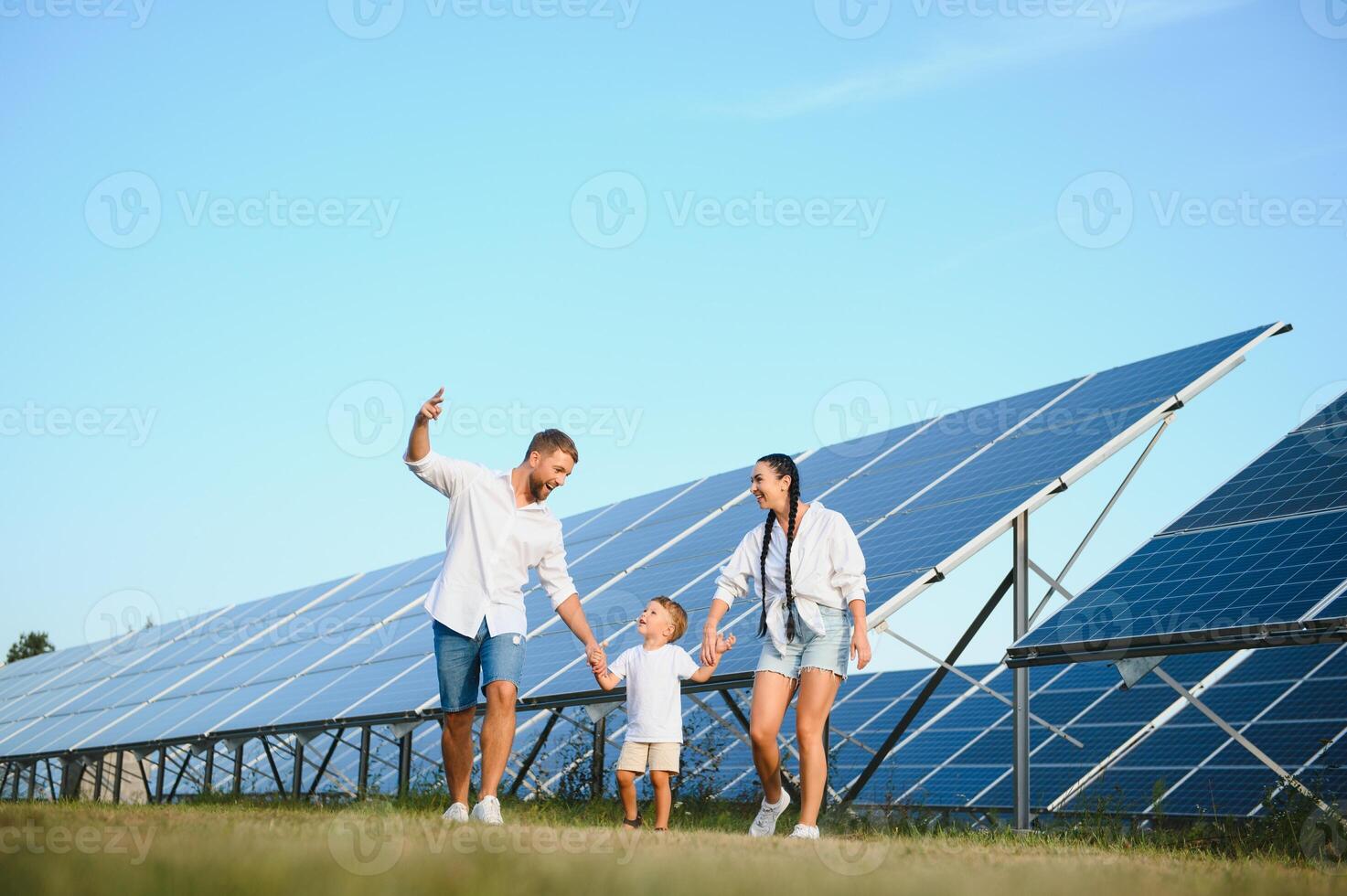 il concetto di verde energia. contento famiglia a piedi e avendo divertimento nel solare pannello campo. verde energia. foto
