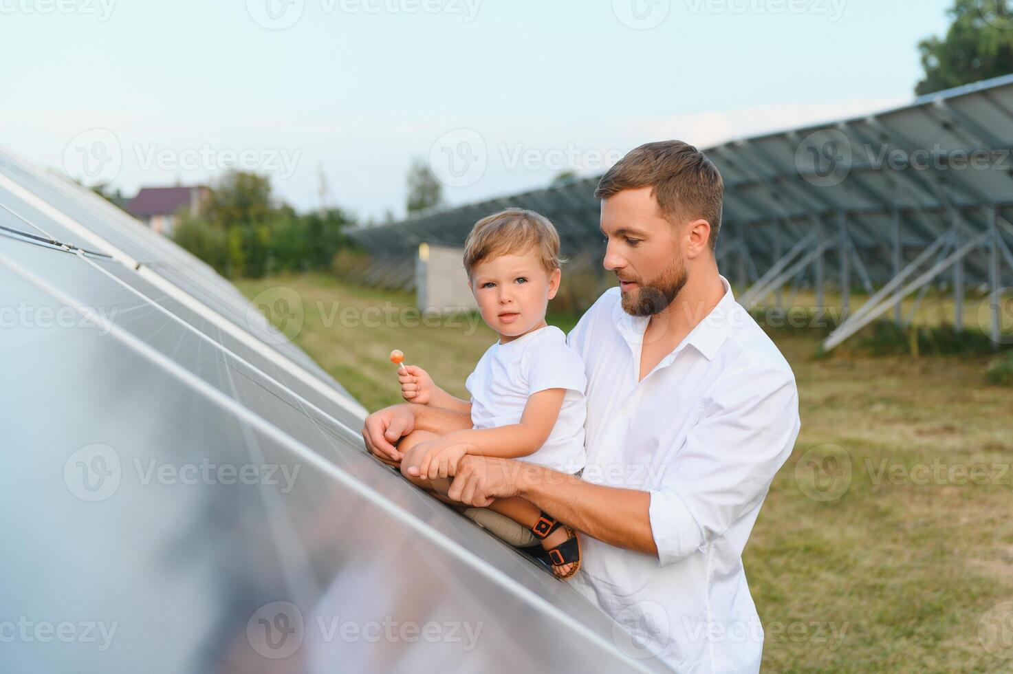 uomo mostrando poco bambino il solare pannelli durante soleggiato giorno. padre presentazione per il suo ragazzo moderno energia risorsa. poco passaggi per alternativa energia. foto