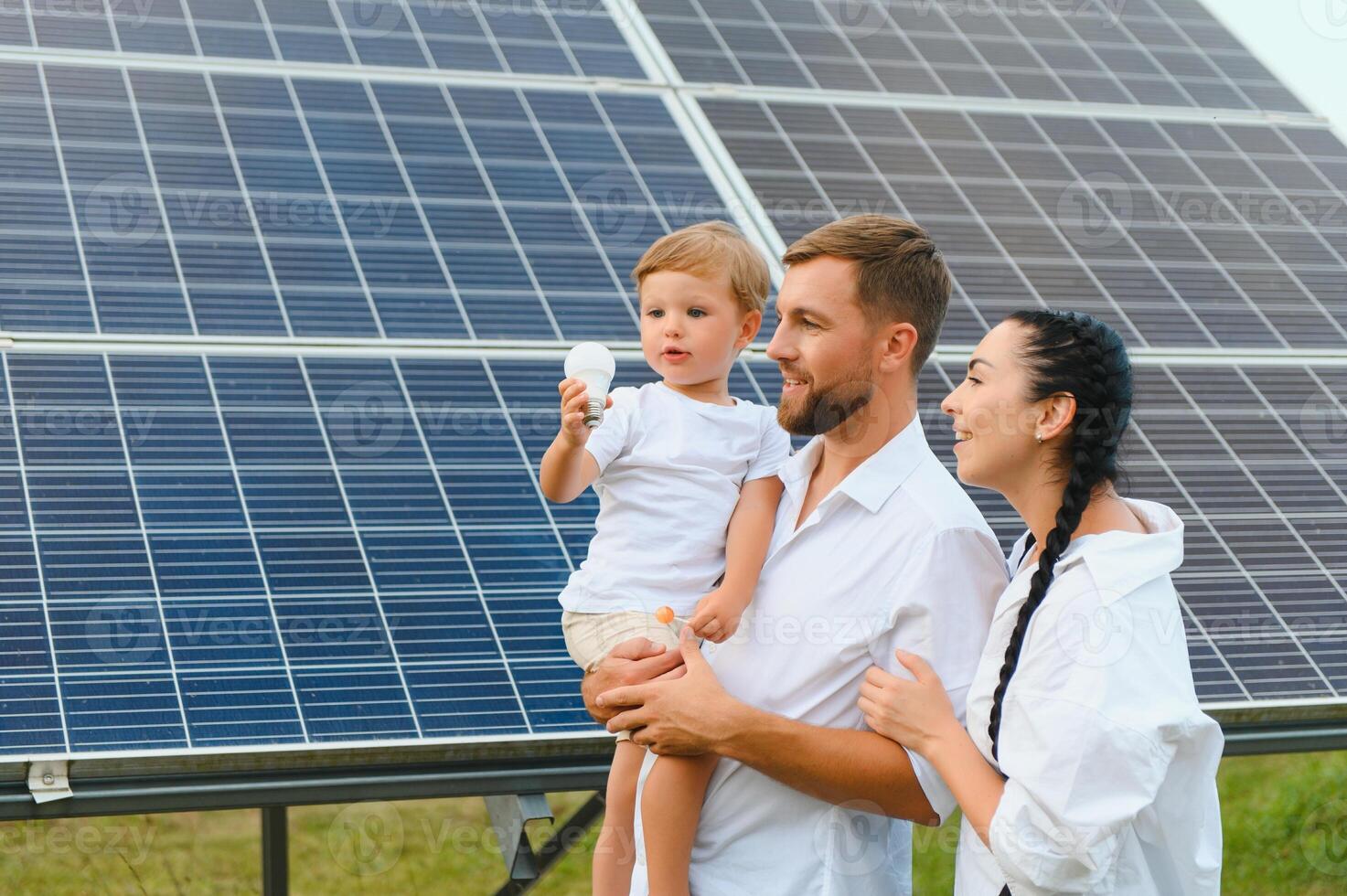 giovane famiglia di tre è accovacciato vicino fotovoltaico solare pannello, poco ragazzo e genitori. moderno famiglia concetto. il concetto di verde energia foto