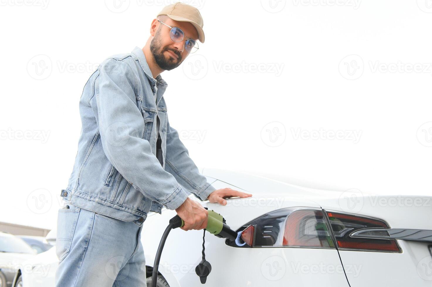 elegante uomo inserti spina in il elettrico auto ricarica presa di corrente foto