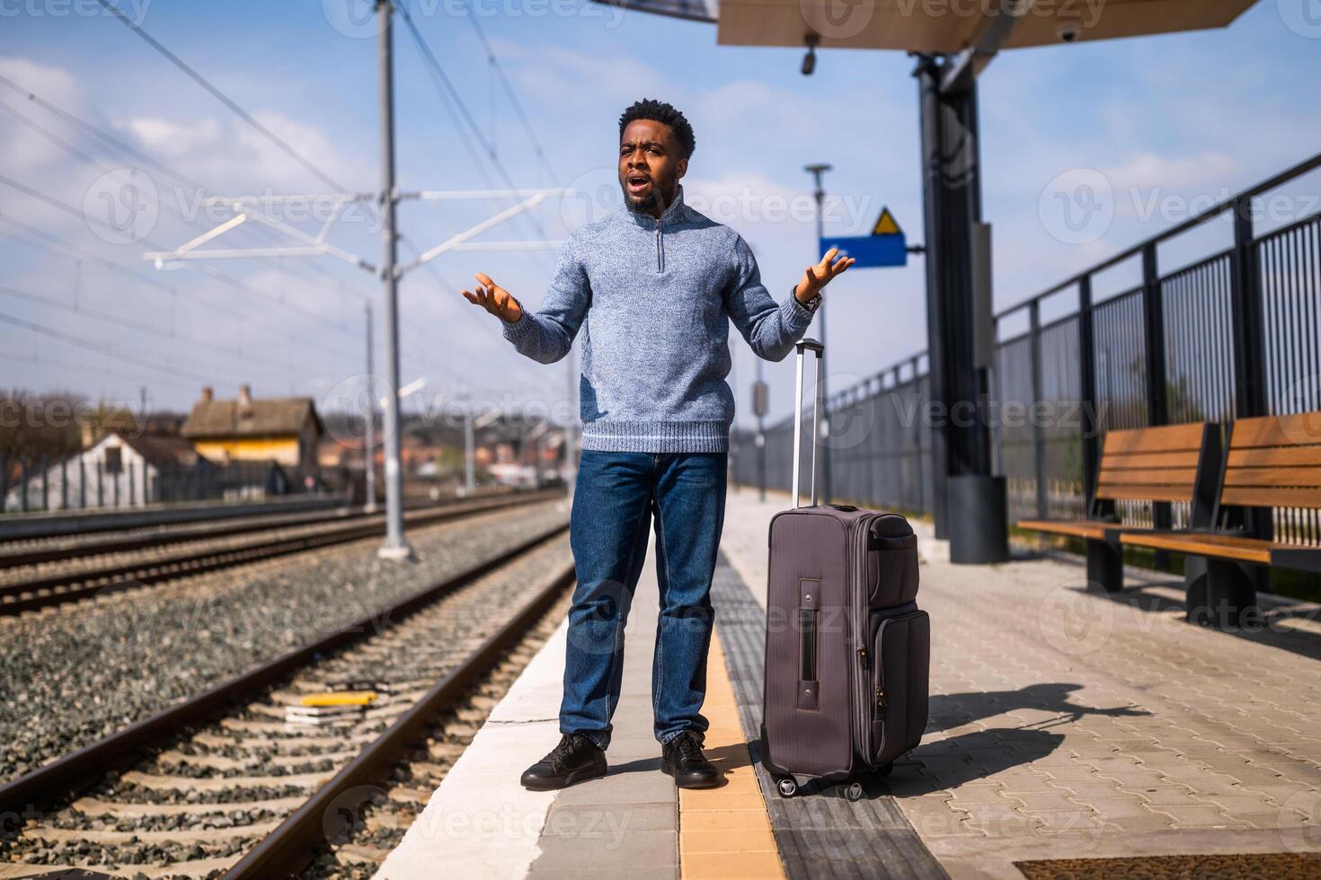 arrabbiato uomo con un' valigia in piedi su un' ferrovia stazione. foto