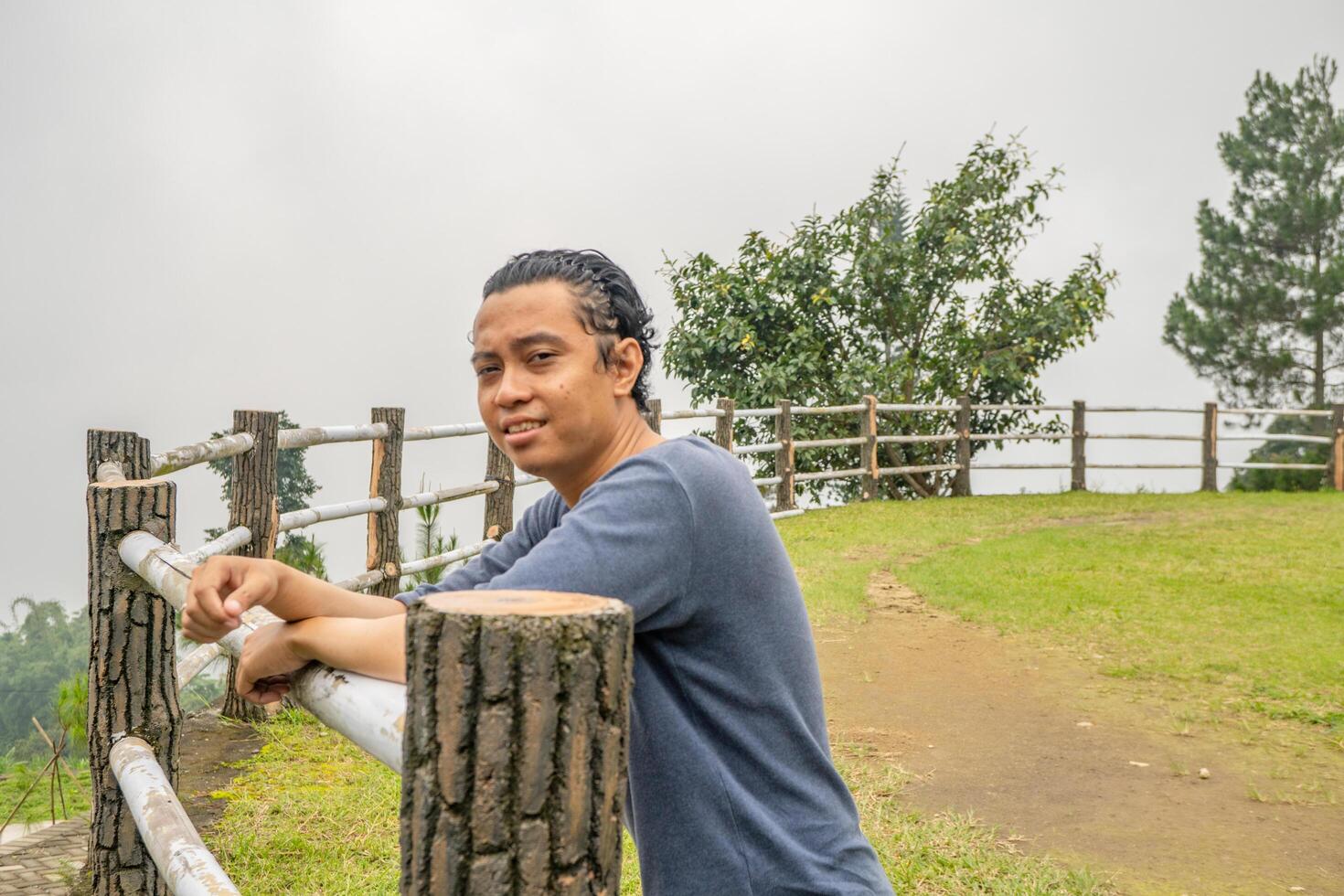 giovane uomo In piedi su il erba campo cavallo arena. il foto è adatto per uso per calma goduto attività, tempo libero attività e parco sfondo.