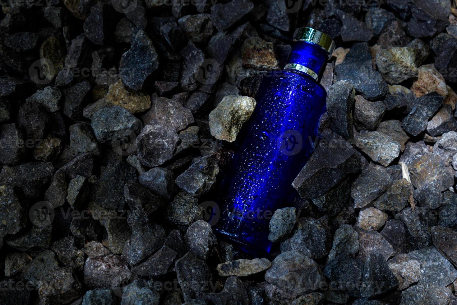 profumo buio blu trasparente bottiglia nel ghiaia o corallo sfondo foto