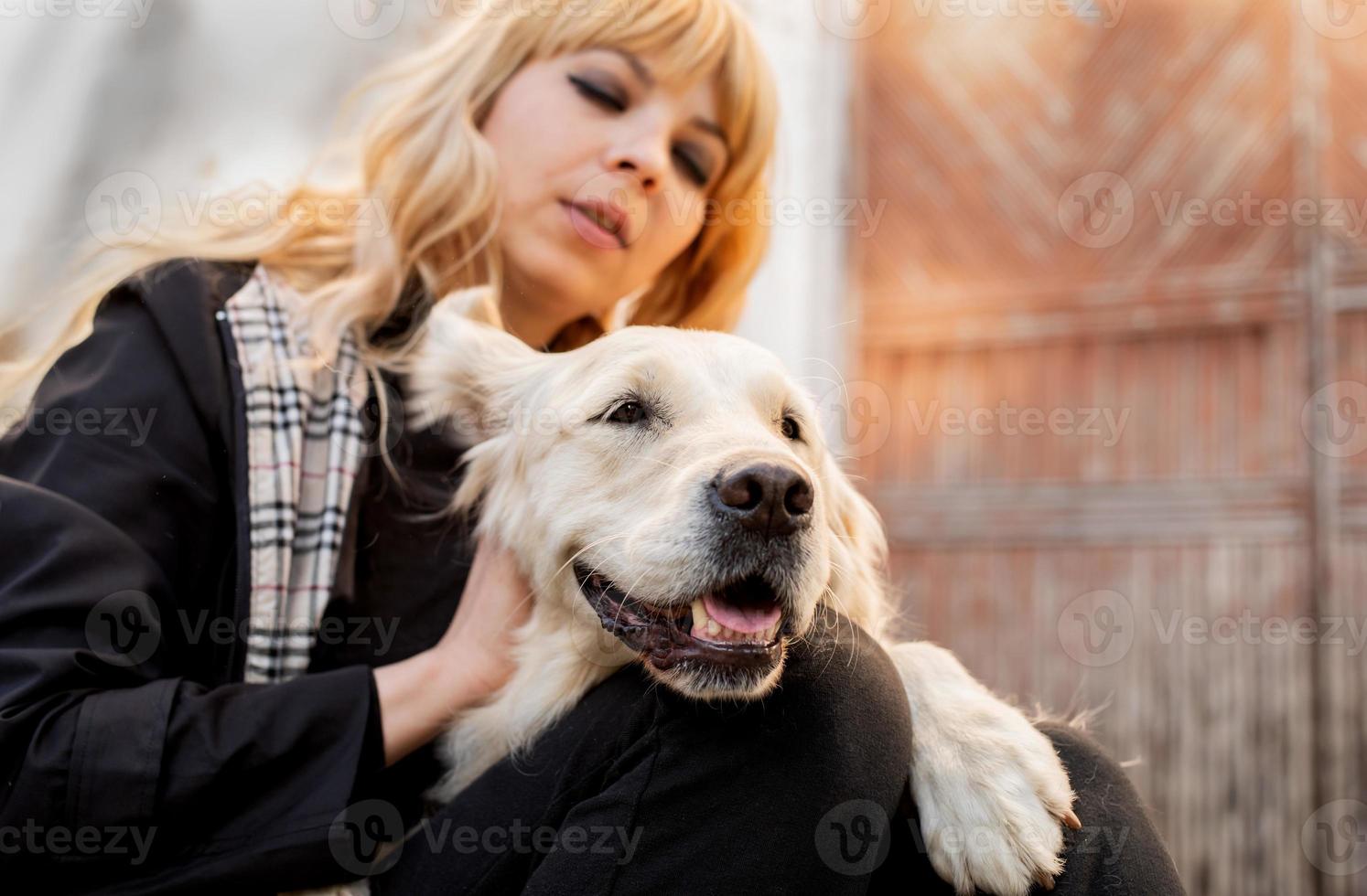 donna bionda che abbraccia il suo cane da riporto foto