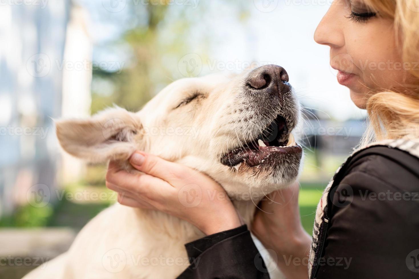 donna bionda che abbraccia il suo cane da riporto foto