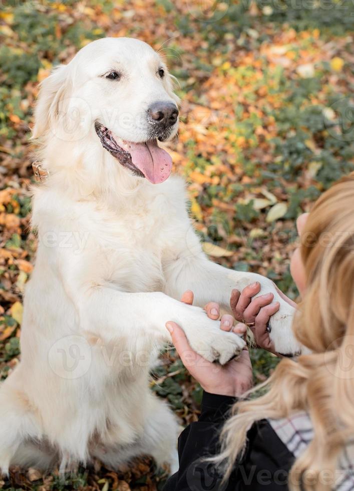 donna bionda che tiene le zampe del suo cane golden retriever nel parco foto