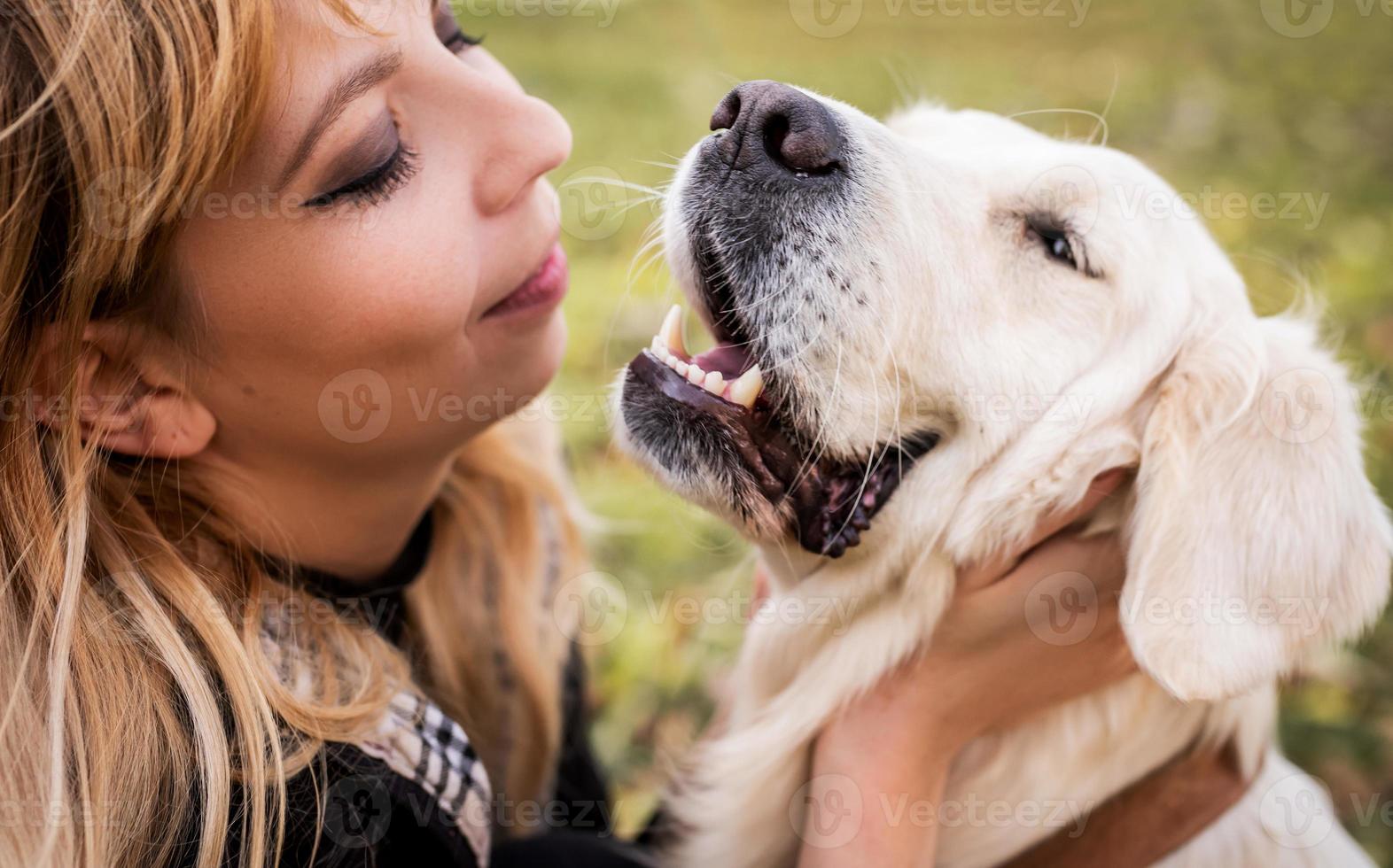 una donna bionda che accarezza il suo cane da riporto nel parco foto