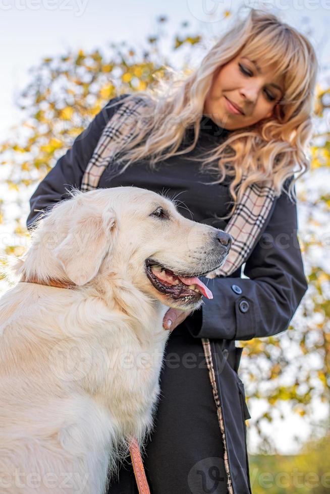 bella donna caucasica bionda che tiene una zampa del cane nel parco foto