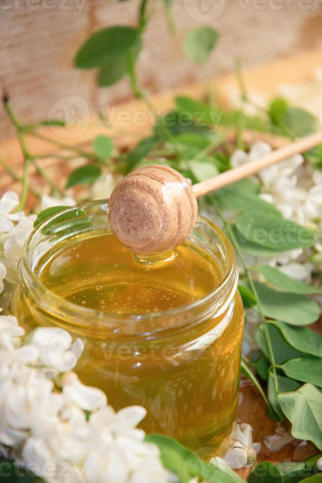 ancora vita di un' pieno vaso di trasparente giallo ocacia miele su il tavolo contro il sfondo di cera favi foto