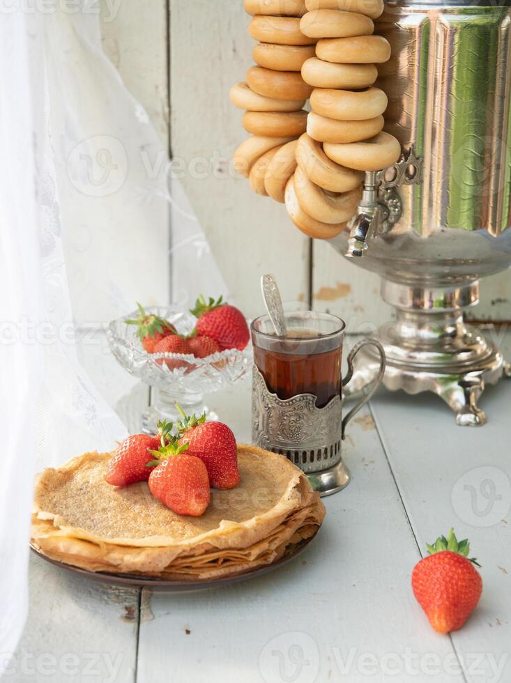 ancora vita nel il russo tradizione per maslenitsa, Pancakes con miele e fragole, tè a partire dal un' samovar con bagel foto